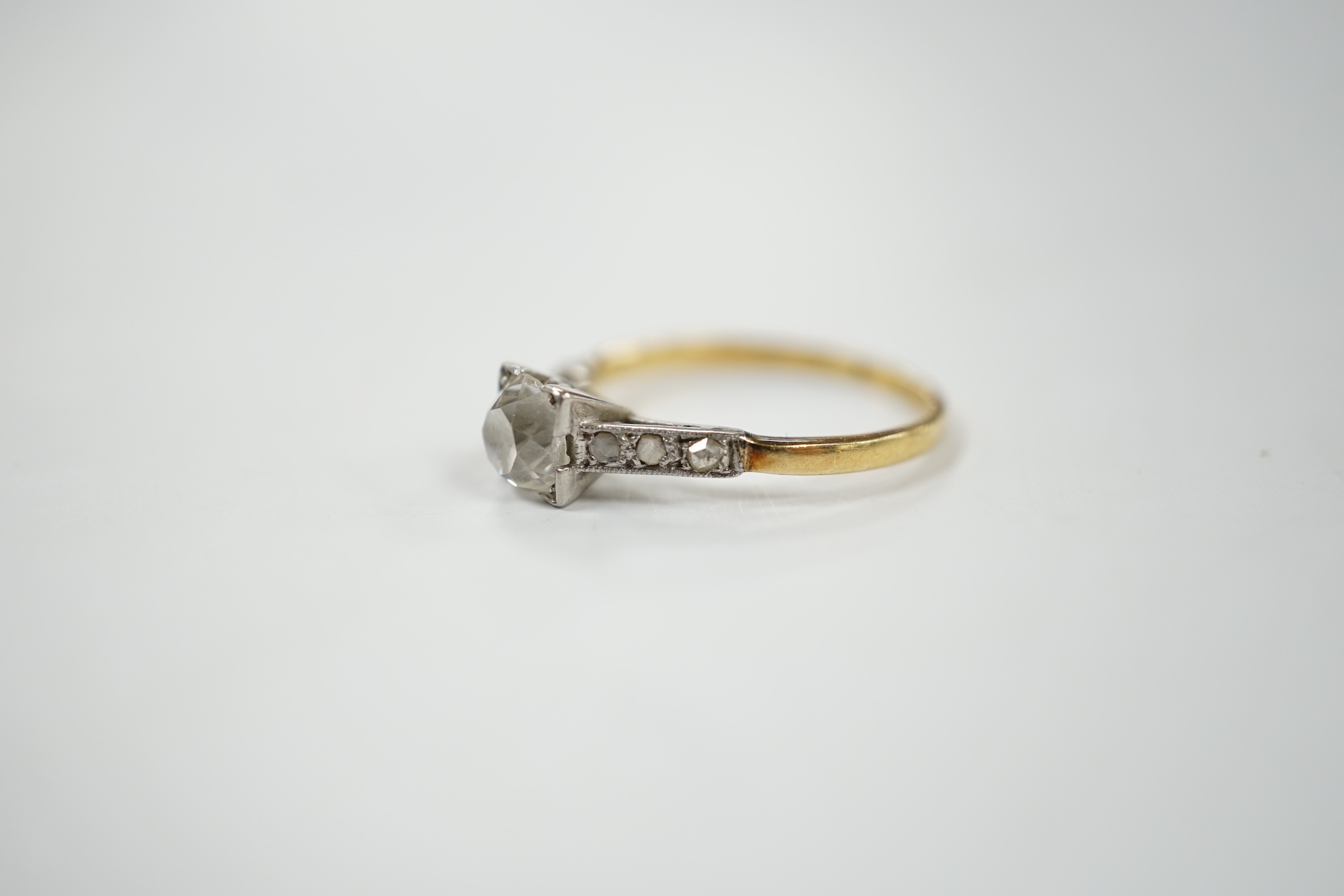 A 1920's yellow metal and single stone old mine cut diamond set ring, with six stone diamond set shoulders, size K/L, gross weight 2.2 grams.